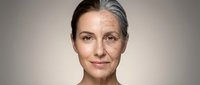 Mature Caucasian woman with gray hair and natural aging lines showing confidence and grace in professional portrait for skincare and wellness campaigns.