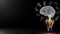 Glowing light bulb with circuit brain and innovation icons on dark background representing creative thinking and technological solutions for business.