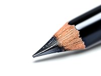Sharp black graphite pencil tip in extreme macro closeup against white background, showing detailed wood texture and lead point for drawing and sketching.