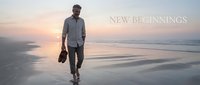 Middle-aged man with dark skin tone walking along empty beach at sunrise, carrying shoes in hand, wearing casual shirt and pants. Serene coastal scene for lifestyle and motivational content.