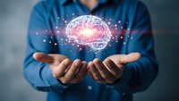 Professional man in blue shirt holding glowing digital brain with neural network connections representing artificial intelligence and innovation.