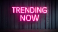 Glowing pink neon sign reading "TRENDING NOW" against dark metallic wall, creating vibrant contrast for social media, marketing, or business concepts.