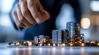Professional hand pointing at illuminated miniature city buildings model with bokeh lights, demonstrating urban development and real estate planning concept.