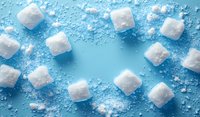 White sugar cubes scattered in circular arrangement on bright blue background with granulated sugar powder, creating minimalist food composition for healthy lifestyle concept.