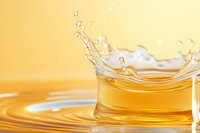 Golden liquid splash with droplets and ripples creating dynamic motion against warm yellow background for beverage and fluid concepts.