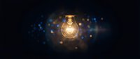 Glowing light bulb with warm filament against dark background with blue and golden bokeh lights for innovation and creativity concepts.