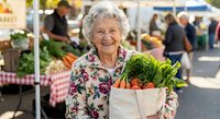 Happy senior Caucasian woman holding fresh vegetables in reusable bag at farmers market, healthy lifestyle and sustainable shopping concept.