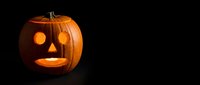 Glowing jack-o-lantern pumpkin with carved face on dark background for Halloween decorations and seasonal marketing materials.
