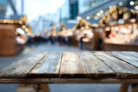 Empty wooden table with blurred Christmas market in background, festive bokeh lights creating warm holiday atmosphere for product display.