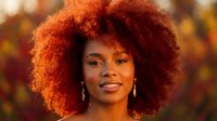 Young African American woman with vibrant curly afro hairstyle smiling warmly in golden autumn light with bokeh background for beauty and lifestyle content.