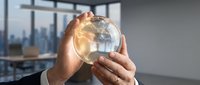 Businessman holding glowing globe in office with city skyline view, representing global business, international commerce, and worldwide connectivity for corporate concepts.