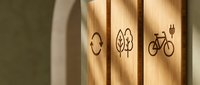 Wooden eco-friendly symbols engraved on natural wood planks featuring recycling, leaf and bicycle icons representing sustainability and green living concepts.