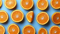 Fresh juicy orange halves arranged in rows on bright blue background, creating modern minimalist pattern for healthy lifestyle and citrus fruit concepts.