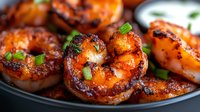 Grilled jumbo shrimp with spicy glaze and charred edges served on black plate, garnished with fresh chopped herbs. Close up view of seafood appetizer.