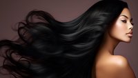 Asian woman with flowing long black hair against brown background, side profile view showcasing natural beauty and healthy shiny hair movement for beauty and cosmetic advertising.