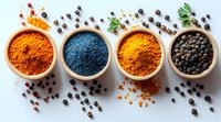Vibrant spices and black peppercorns in wooden bowls on light background, overhead view of turmeric powder, blue spirulina and scattered seasonings.