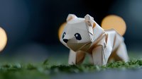 White origami cat paper craft sitting on green moss with warm bokeh lights in dark background creating magical atmosphere for creative projects.