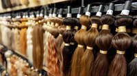 Rows of natural hair extensions in various shades of brown, blonde and dark colors hanging in beauty salon. Close up view of premium quality human hair bundles for styling.