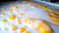 Macro shot of water droplets with vibrant orange and yellow light reflections creating abstract pattern on wet glossy surface. Artistic photography background.