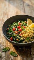 Fresh tabbouleh salad with parsley, tomatoes, bulgur wheat and lemon in dark bowl on rustic wooden table. Healthy Mediterranean cuisine for restaurant menus.
