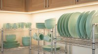 Modern kitchen organization with mint green ceramic dinnerware set displayed on chrome wire shelving racks under wooden cabinets with LED lighting.