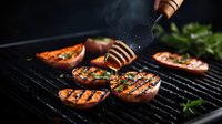 Grilled peaches on barbecue grill with honey drizzle from wooden dipper, creating caramelized fruit dessert with fresh herbs against dark background.