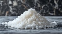 White coarse sea salt crystals pile on wooden surface with blurred natural background for cooking seasoning and food preparation.