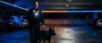 Security guard with police dog patrolling underground parking garage at night. Professional law enforcement officer on duty with K9 partner in urban setting.
