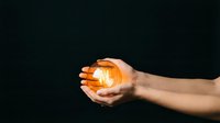 Hand holding glowing golden sphere against dark background, symbolizing energy, innovation, and success for business and technology concepts.