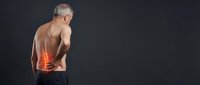 Shirtless senior man holding lower back with glowing red spine highlight indicating pain or injury on dark background.