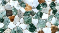 Mosaic pattern of irregular marble and stone pieces in green, white, and brown shades creating abstract geometric background for interior design projects.