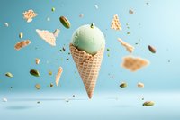 Pistachio ice cream scoop in waffle cone floating with scattered nuts and cone pieces against light blue background, dynamic food levitation composition.