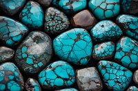 Polished turquoise stones with natural web-like patterns and dark matrix veining create striking texture and contrast in close-up view. Precious gemstones for jewelry making.