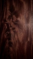 Dark brown wood grain texture with natural knots and swirls, suitable for backgrounds, design elements, and woodworking projects.