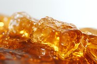 Golden ice cubes in amber liquid with bubbles and light reflections create dynamic texture and movement, close-up macro photography showing refreshing cold drink.