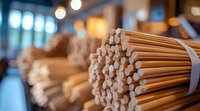 Bundles of wooden chopsticks arranged in rows with soft bokeh background, selective focus on front bundle showing natural bamboo texture and warm lighting.