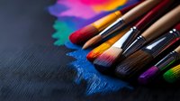 Colorful artist paintbrushes with vibrant paint strokes on dark textured background, arranged diagonally with dramatic lighting for creative and artistic concepts.