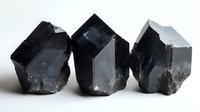 Black quartz crystal points with natural rough texture and geometric shapes on white background, mineral specimens showing raw crystalline structure and dark coloring.