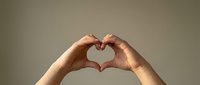 Hands forming heart shape gesture against neutral background expressing love affection and positive emotions for romantic wellness concepts.