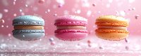 Colorful French macarons in gray, pink and orange flavors arranged on marble surface with falling sugar crystals and soft pink bokeh background.