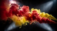 Vibrant red and yellow powder explosion creating dramatic cloud formations against dark background with dynamic lighting effects.
