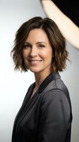 Professional businesswoman with short brown hair smiling confidently in dark blazer for corporate marketing and leadership content.