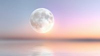 Large full moon rising over calm ocean waters during sunset with pink and purple sky creating romantic atmospheric seascape for meditation and wellness content.