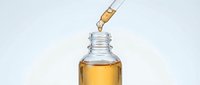 Dropper dispensing golden oil serum into glass bottle against white background, suitable for cosmetics, skincare, and wellness product packaging design.