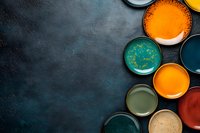 Colorful paint cans with vibrant pigments arranged on dark textured surface for creative projects and artistic endeavors.