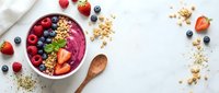 Healthy acai smoothie bowl topped with fresh berries, granola and nuts on white background. Nutritious breakfast meal with antioxidant superfoods for wellness.
