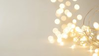 Warm golden fairy lights creating soft bokeh glow on neutral beige background for holiday decorations and festive celebrations.
