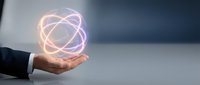 Businessman hand holding glowing atom symbol with orbital electrons, representing science, technology, innovation, and nuclear energy research for corporate and educational use.