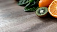 Fresh kiwi and orange slices arranged with green leaves on wooden surface, ideal for food and beverage marketing, healthy eating content, and culinary design projects.