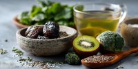 Healthy superfood ingredients including fresh kiwi, broccoli, dates, seeds and herbal tea arranged on rustic surface for nutritious meal preparation.